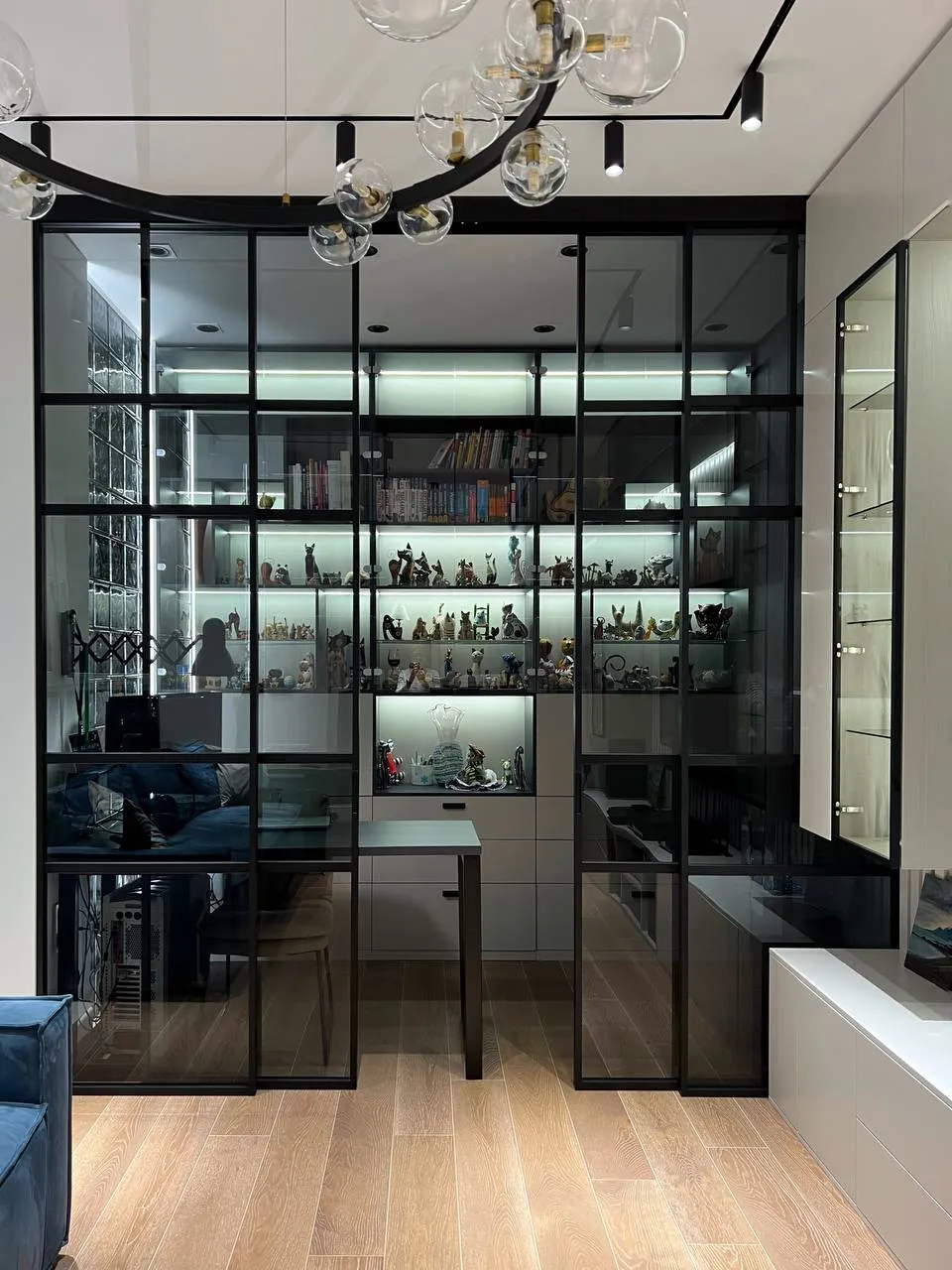 Зона кабинета, отделенная от гостиной прозрачными стеклянными межкомнатными перегородками от производителя Gintereo