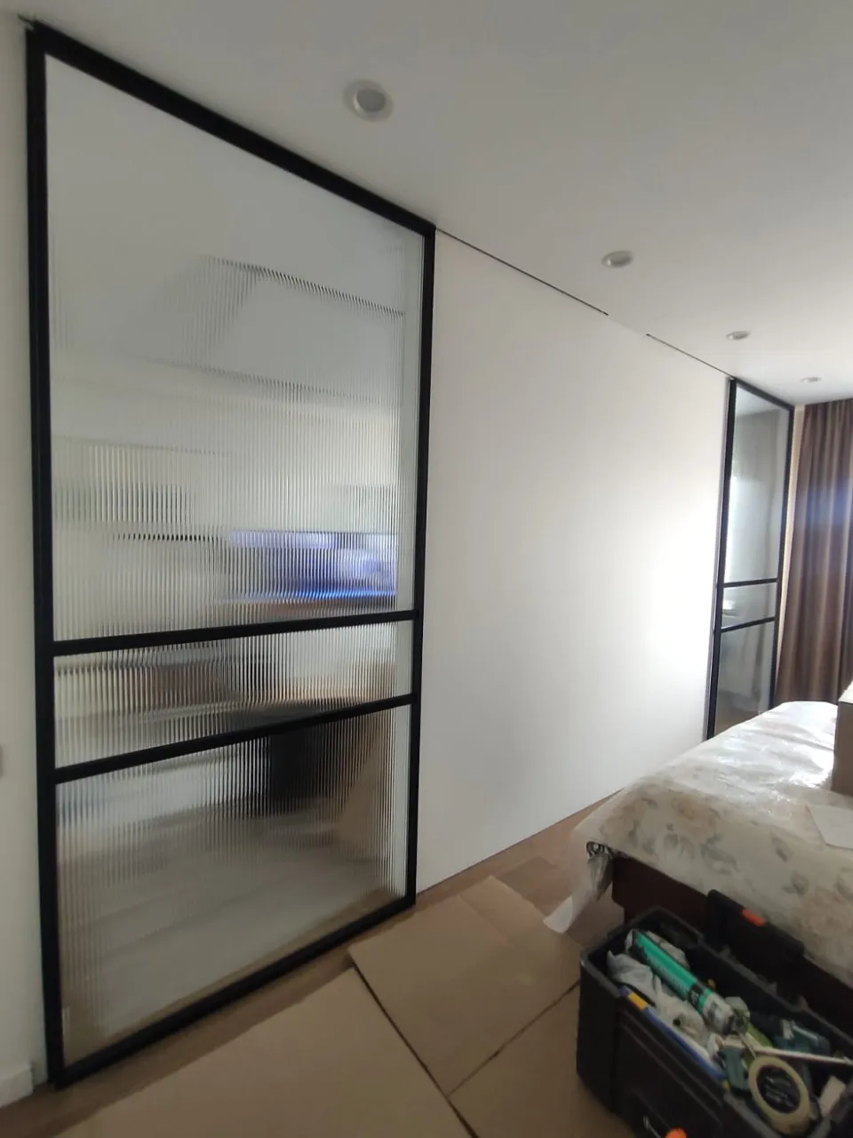 Стеклянные раздвижные перегородки из рифленого стекла Gintereo в зоне спальни. Купить, заказать лофт перегородки в Москве