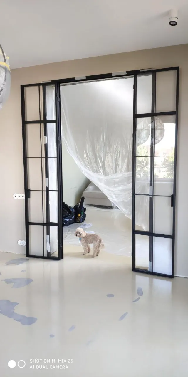 Пудель стоит в проеме межкомнатной распашной перегородки в стиле лофт, сделанной Gintereo. Купить под заказ в Москве, СПБ