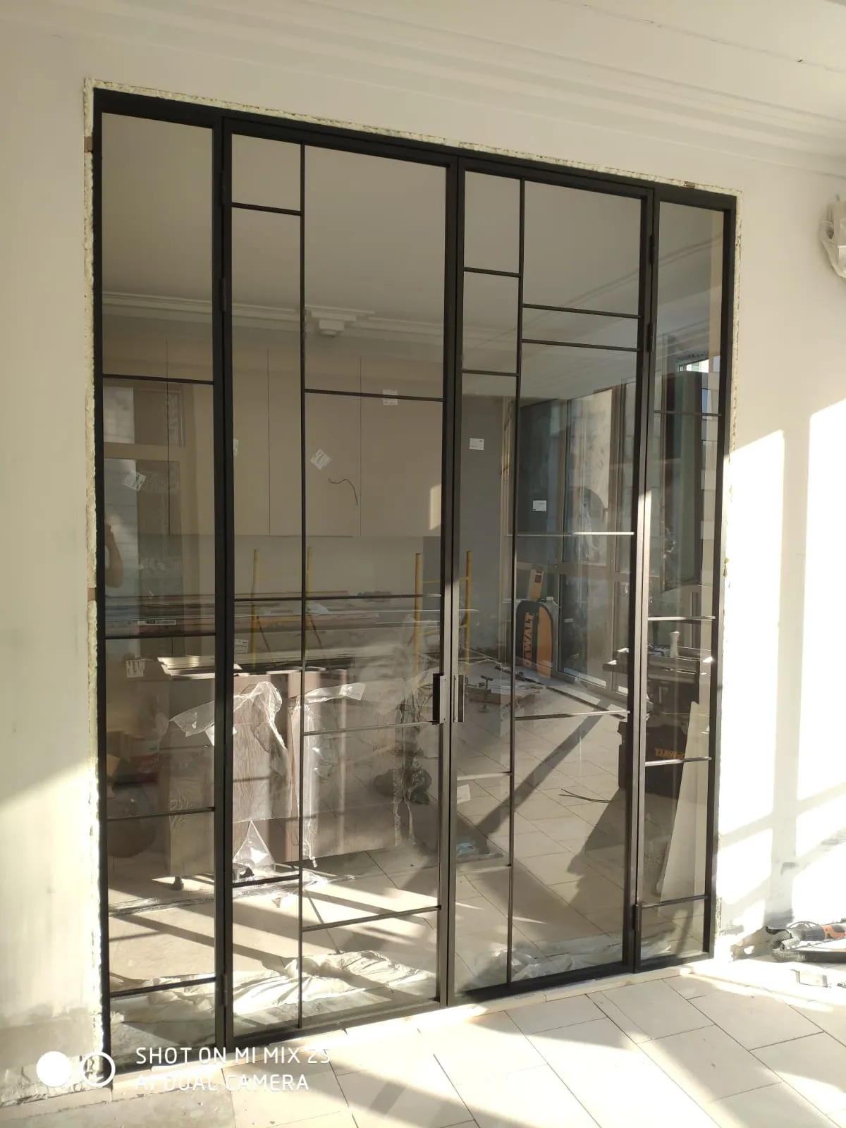 Монтаж распашной межкомнатной перегородки из стекла и черного алюминиевого профиля для зонирования кухни. Проект Gintereo