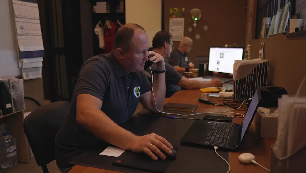 Эксперт Gintereo консультирует клента по телефону в офисе, по вопросам установки межкомнатных перегородок из стекла