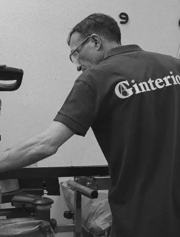 Сотрудник Gintereo работает на производстве лофт перегородок из алюминия и стекла, используя циркулярную пилу.