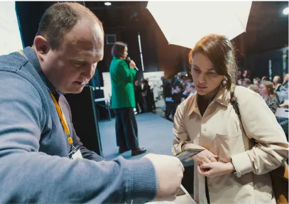 Эксперт Gintereo консультирует девушку на профильной выставке по вопросам установки межкомнатных перегородок из стекла