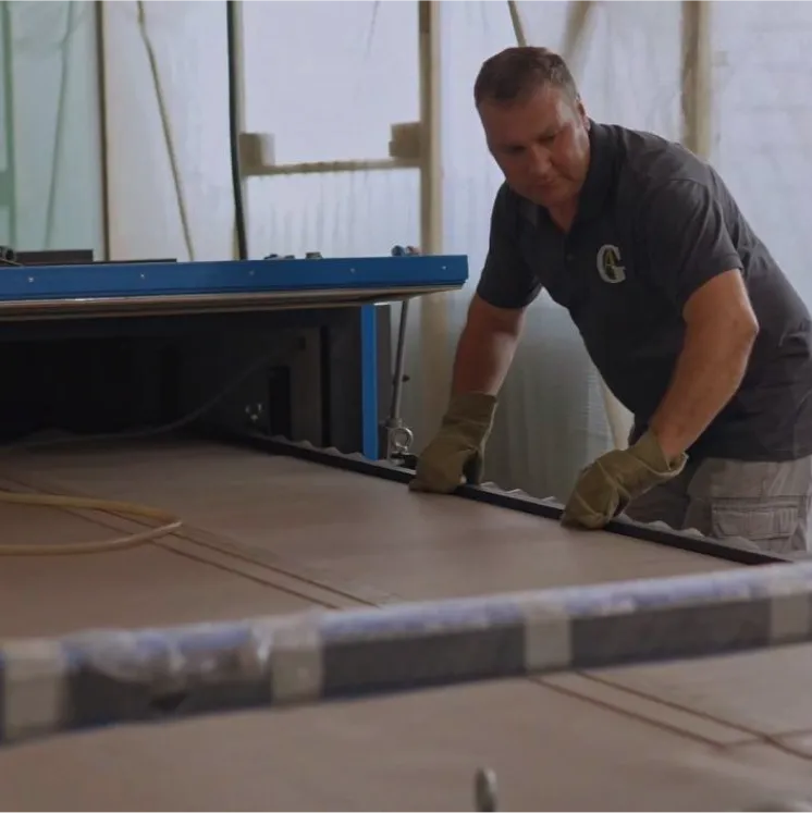 Сотрудник Gintereo на производстве в цеху. Работает с алюминиевым профилем для межкомнатных перегородок для зонирования